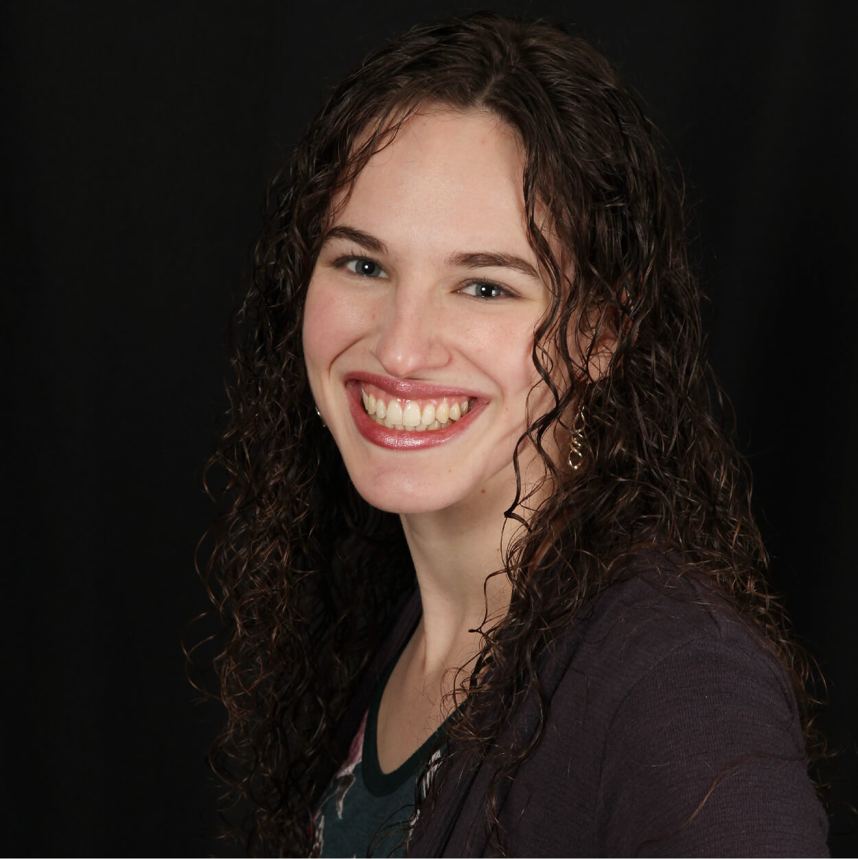 A lady with Curley hairs smiling at the camera